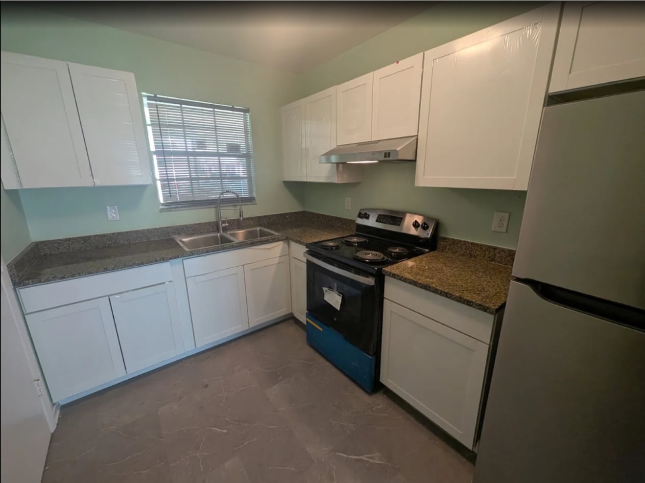 Kitchen cabinets repainted white with granite countertops and fresh green walls in Ocala, FL